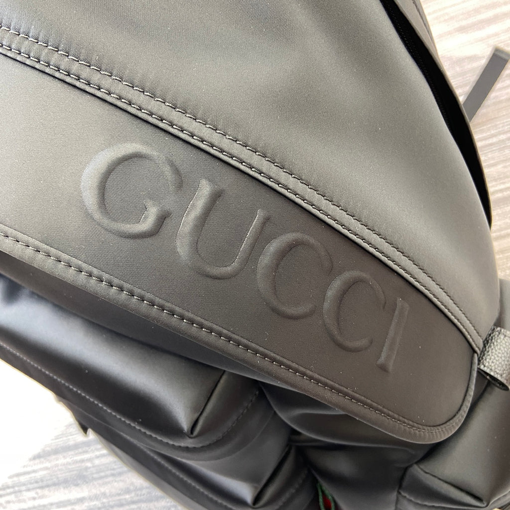 Gucci embossed lettering on black backpack flap with stitched border