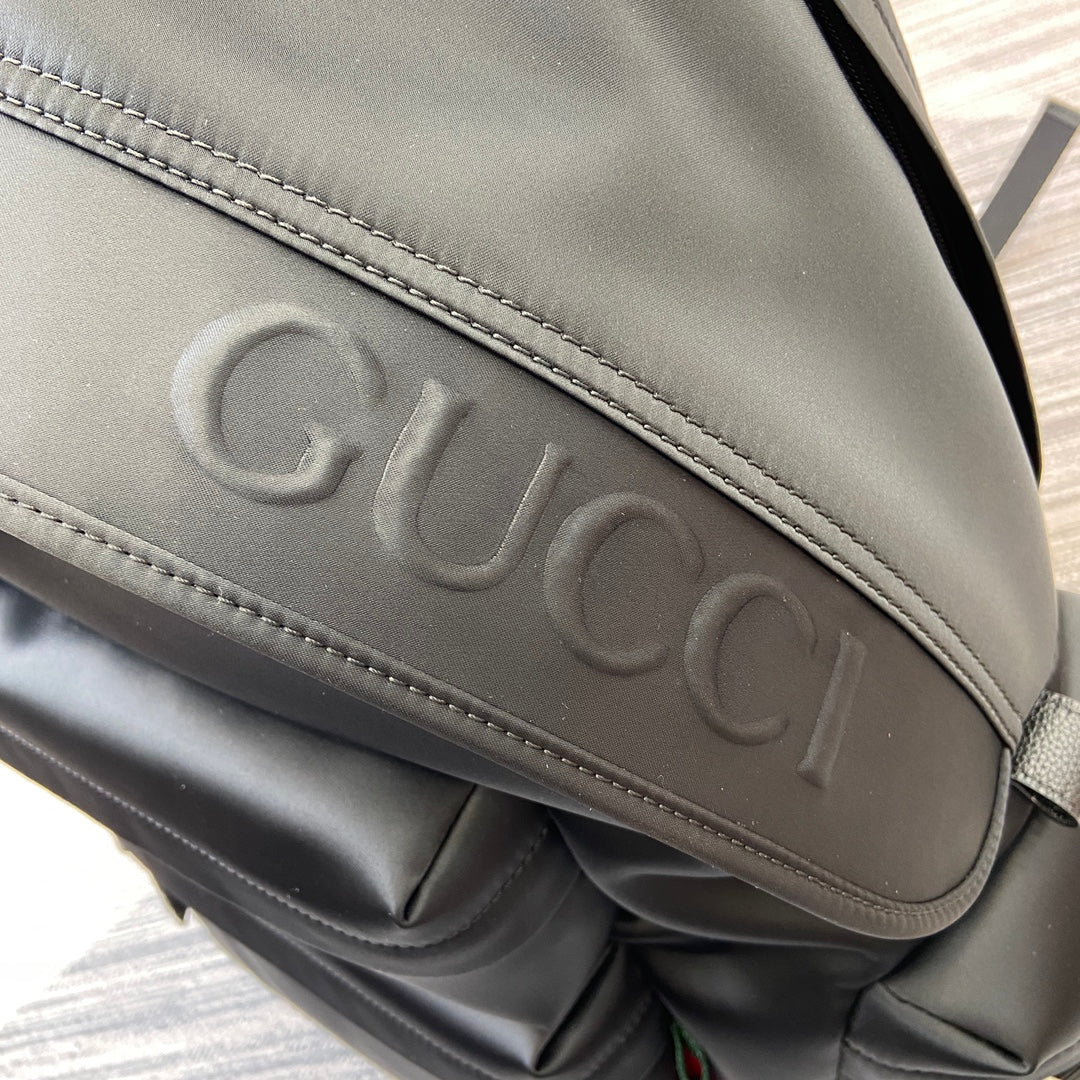 Gucci embossed lettering on black backpack flap with stitched border