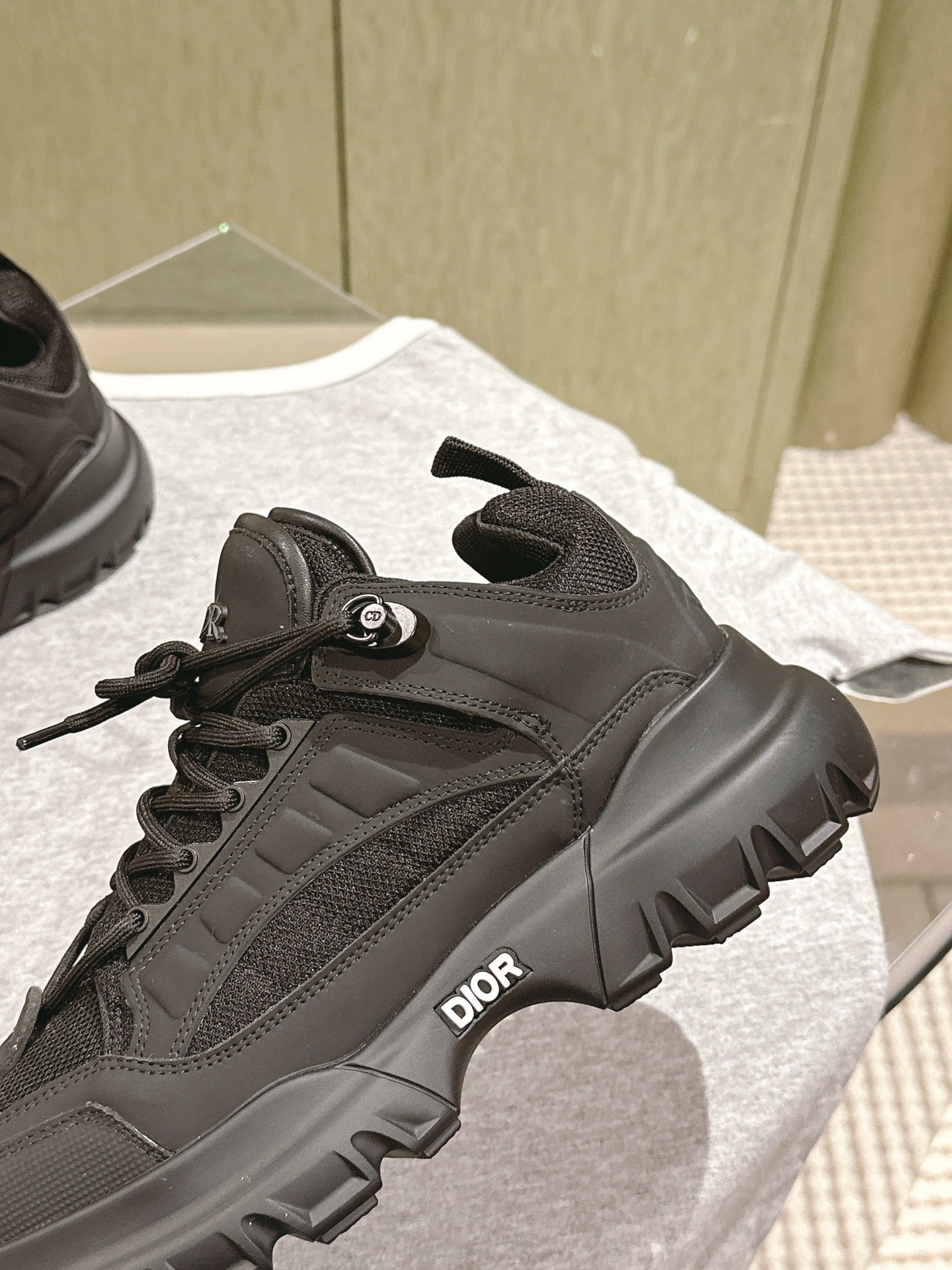 Dior unisex sneaker detail: black strap and laces over chunky treaded sole