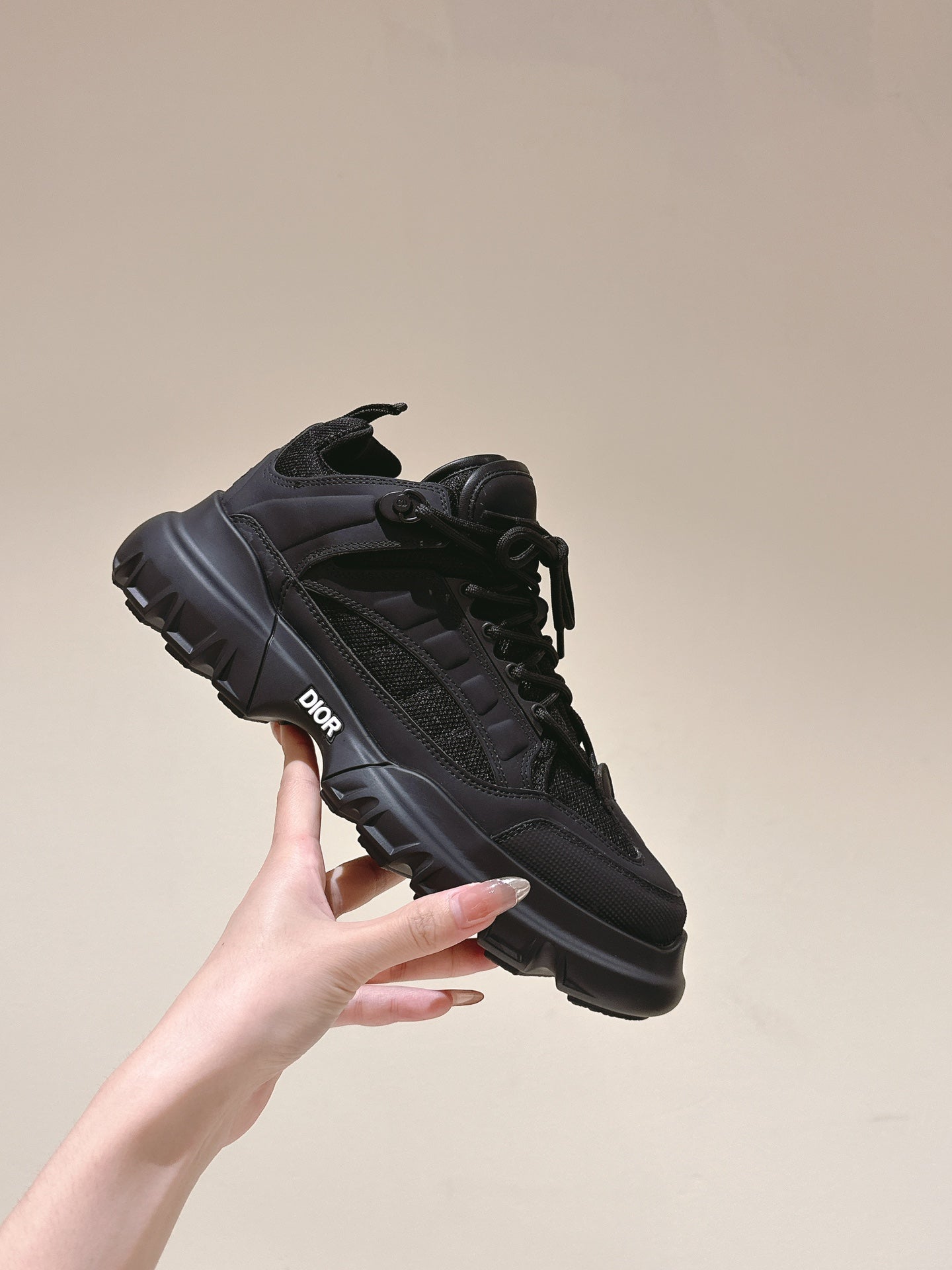 Dior unisex black sneakers held in hand, lace-up with chunky side sole