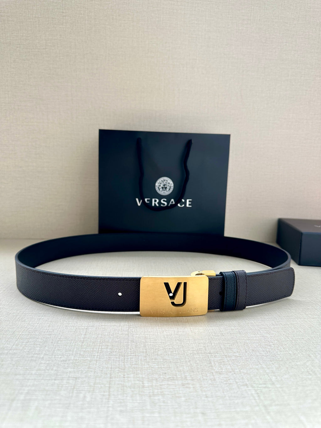 Leather belt with dark blue strap and gold square buckle with VJ logo
