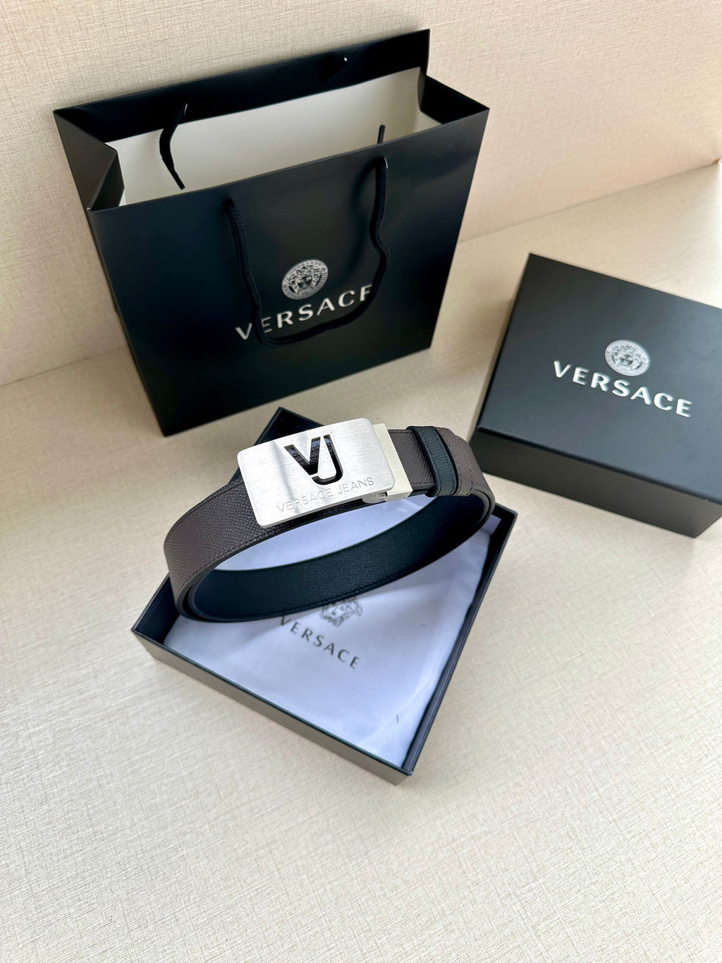 Leather belt with dark strap and white buckle plate with VJ logo