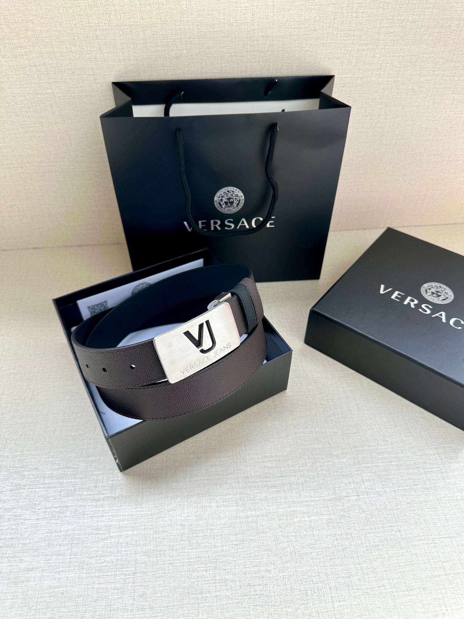 Leather belt with dark strap and white buckle plate with VJ logo