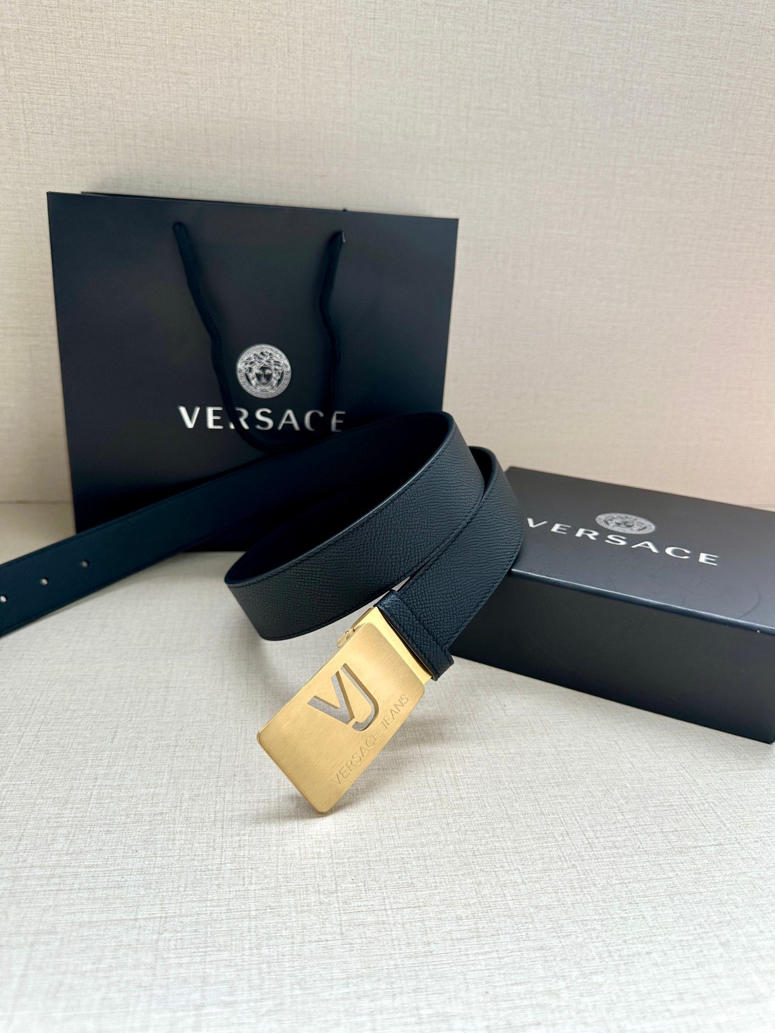 Versace belt with dark blue strap and gold-tone square VJ logo buckle