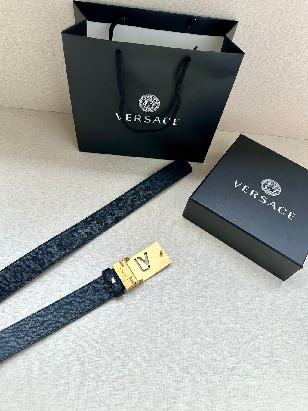 Dark blue belt with gold-tone square VJ logo buckle and perforated holes