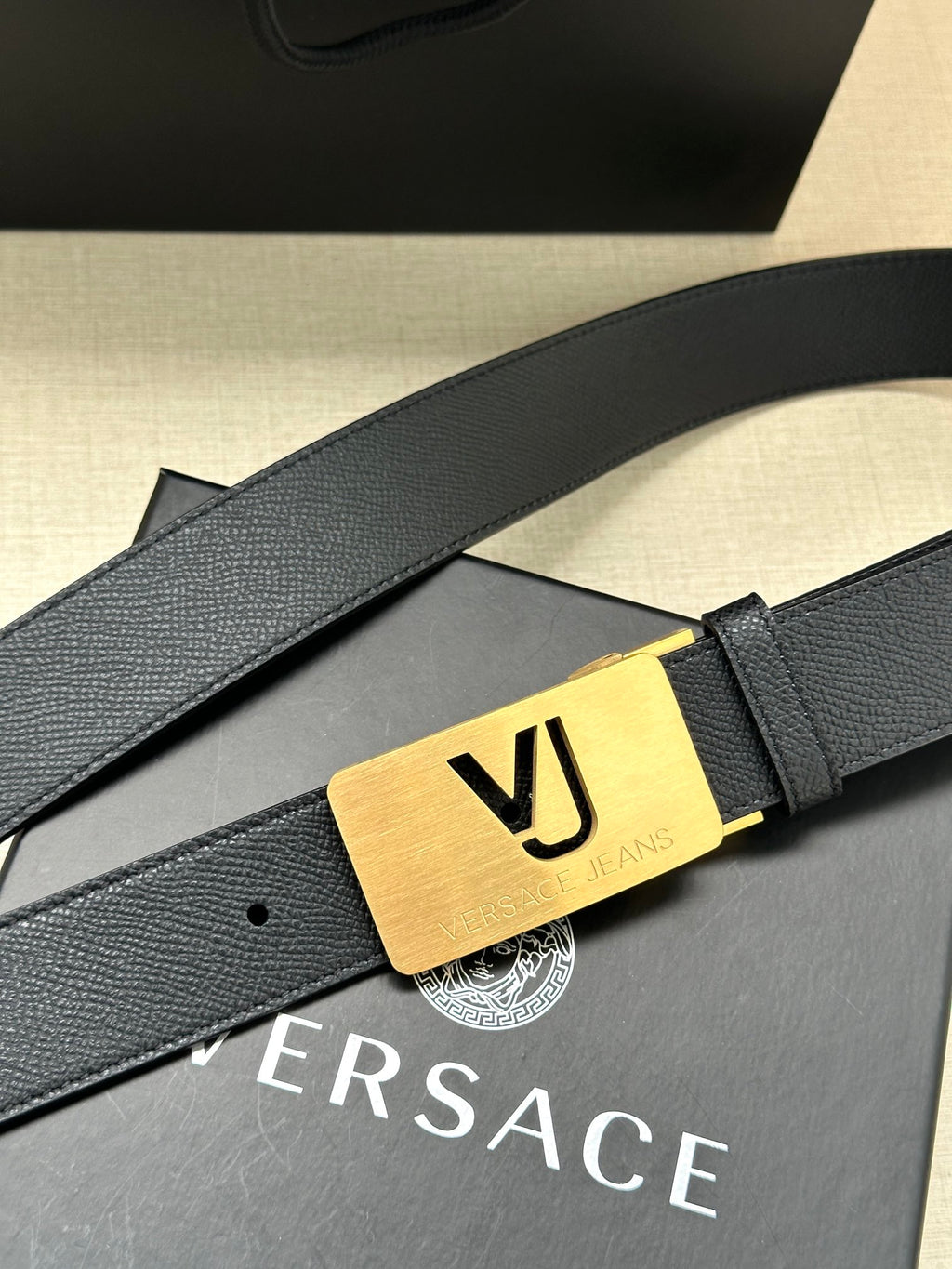 Dark blue leather belt with gold VJ logo buckle and engraved bar