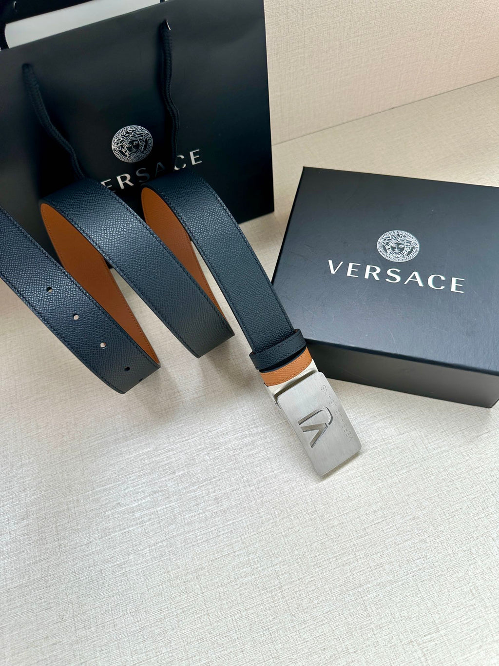Versace belt with dark leather strap, tan underside, silver VJ buckle and holes.