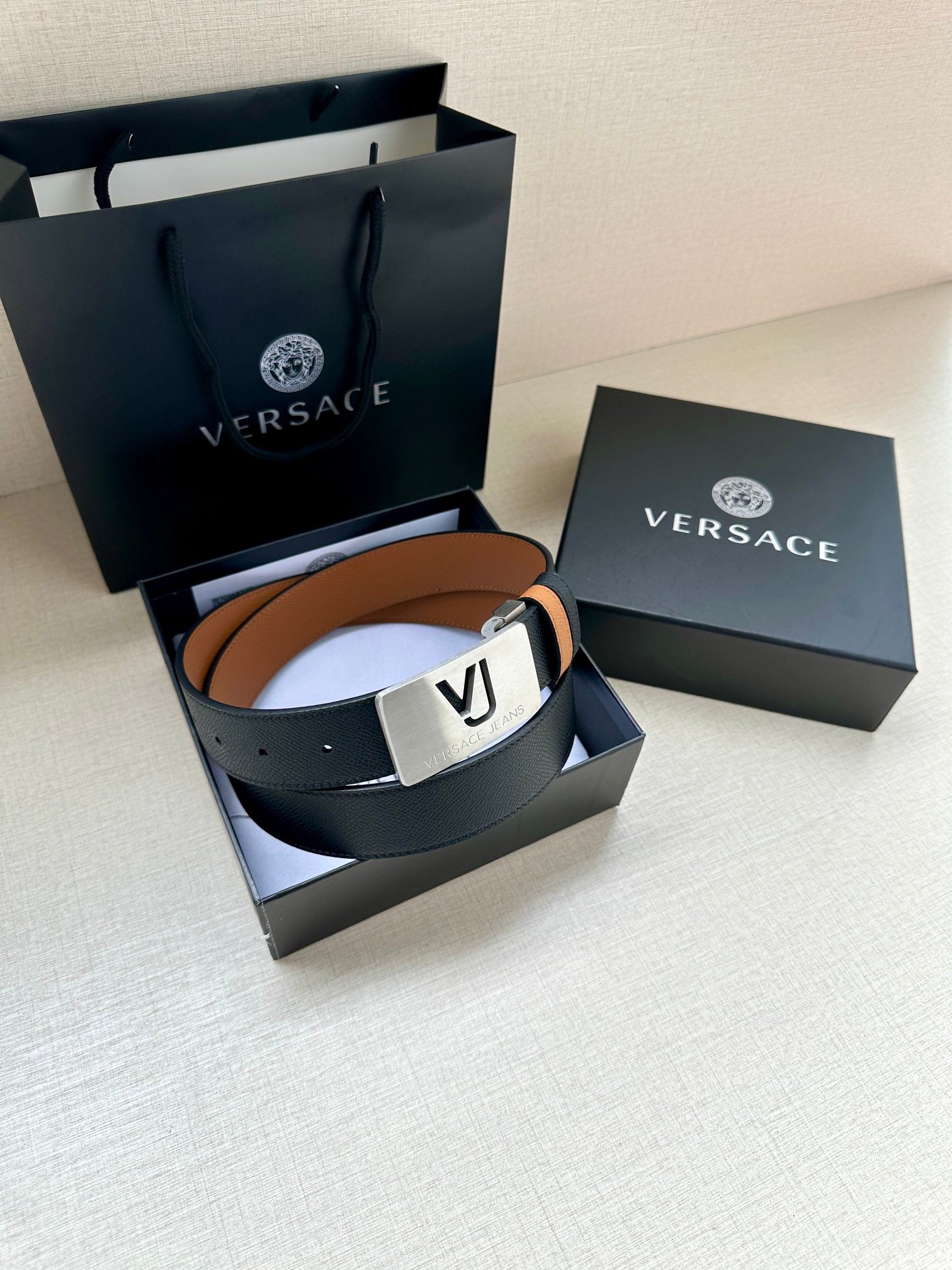 Versace belt with dark leather strap and silver square VJ buckle.