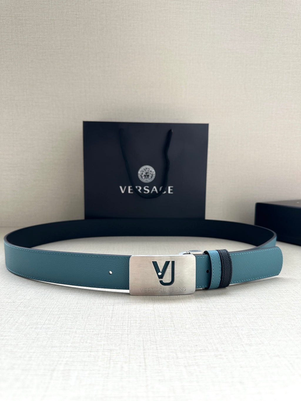 Two-tone leather belt with turquoise strap, silver metal buckle, and logo studs