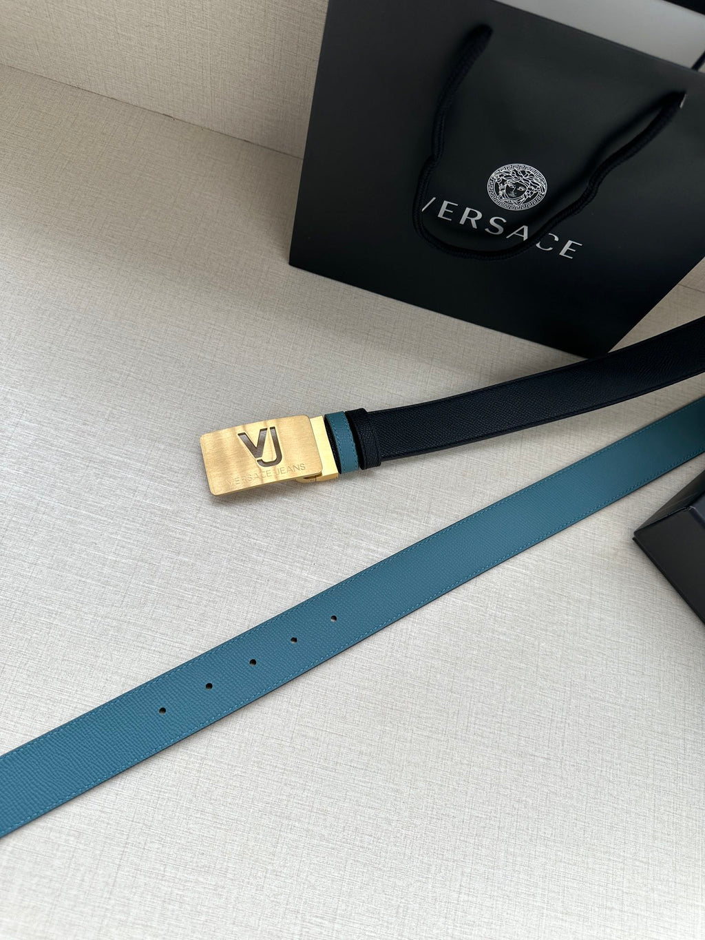 Two-tone leather belt with gold buckle end and perforated strap holes