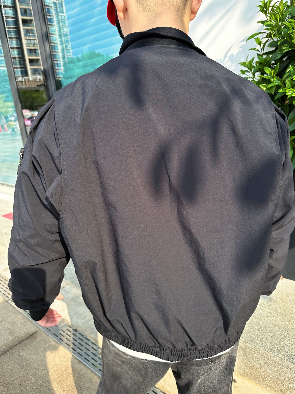 Back view of a black jacket with textured fabric and ribbed waistband