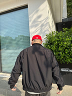 Back view of a black jacket with stand collar and ribbed hem