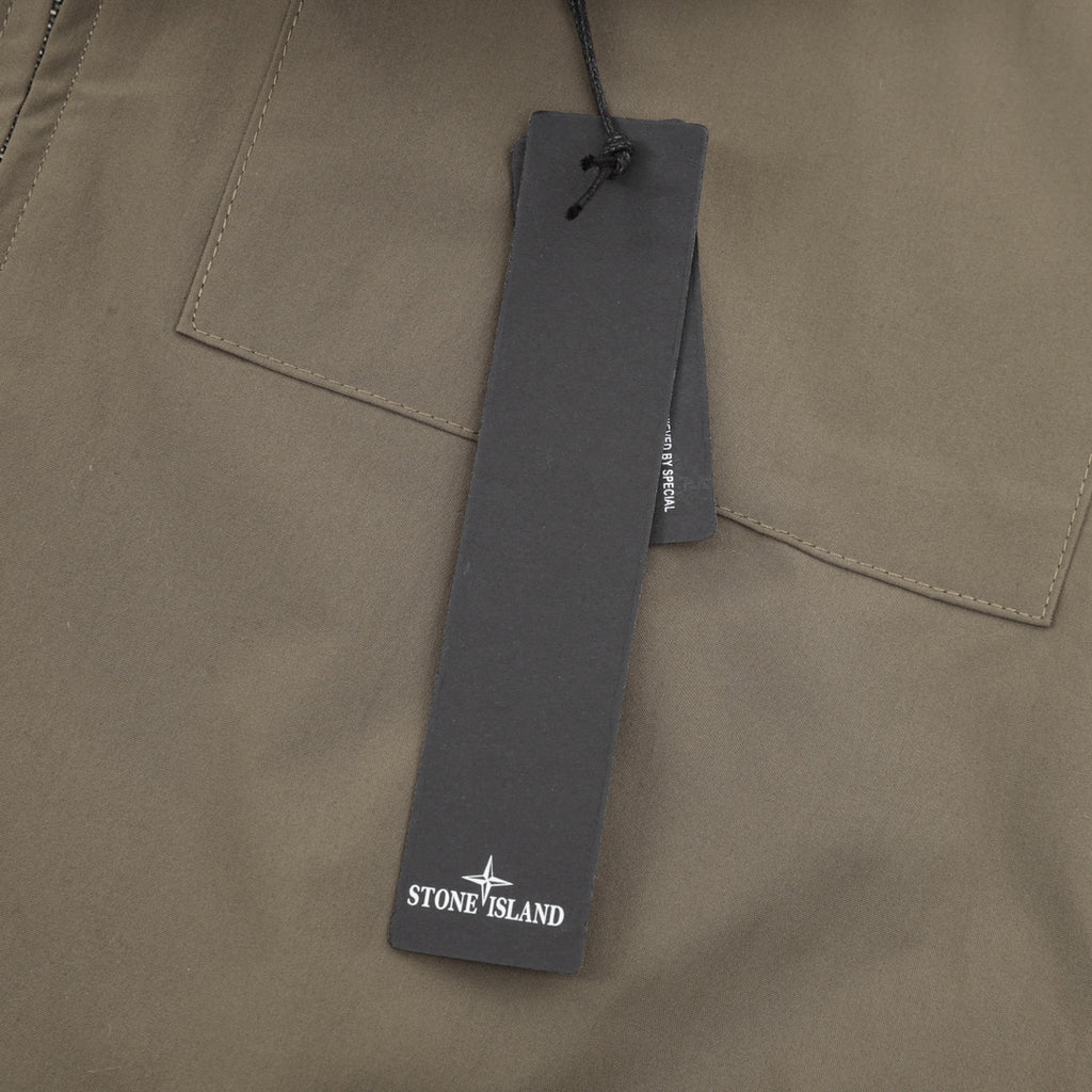 Stone Island garment tag on olive bomber jacket near chest pocket