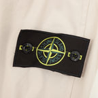 Light beige jacket with black fabric brand patch and green logo on sleeve