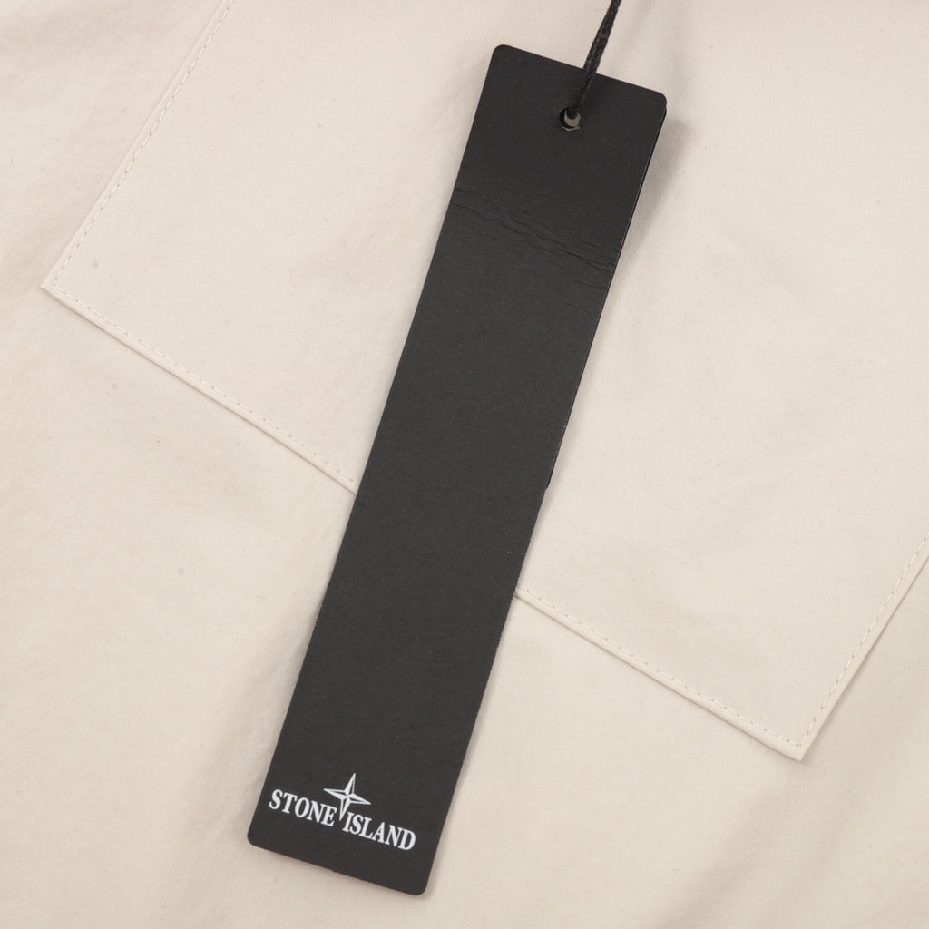 Stone Island size tag hanging on cream jacket front