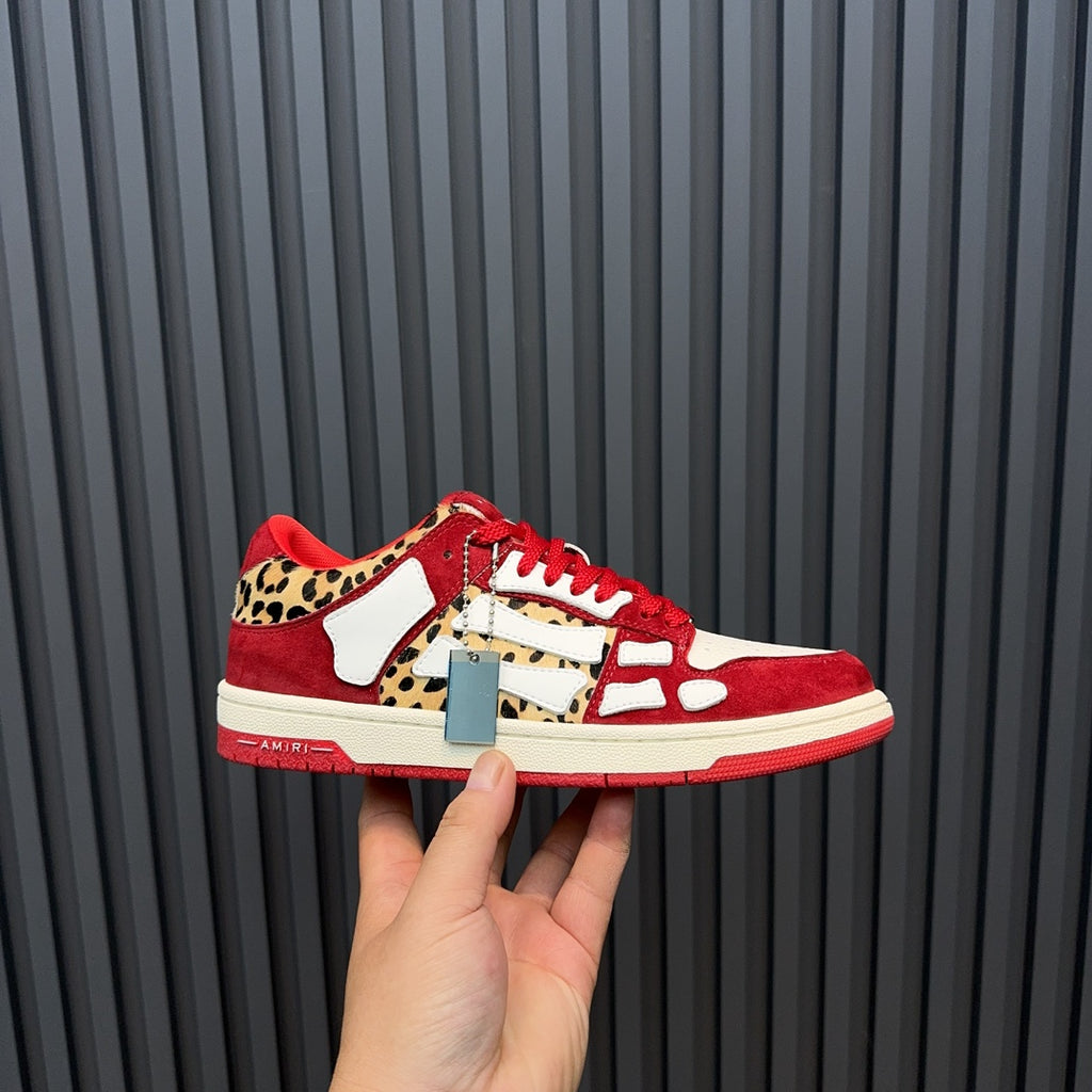 Red Amiri sneakers with white panels, leopard trim, and metallic logo tag