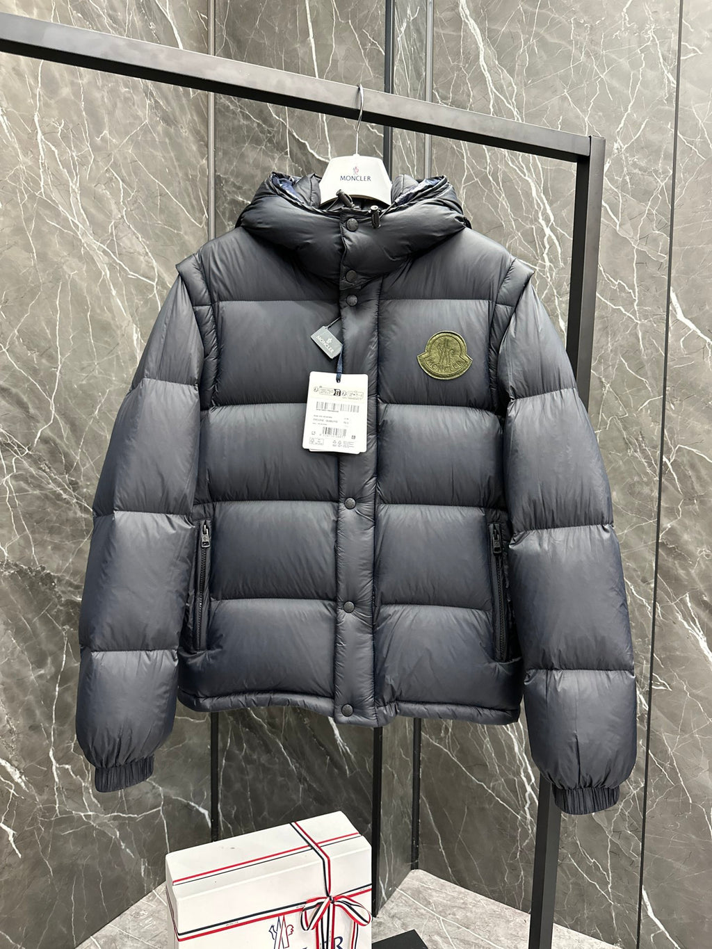 Long hooded puffer jacket, dark fabric, front button placket, hooded collar and logo patch