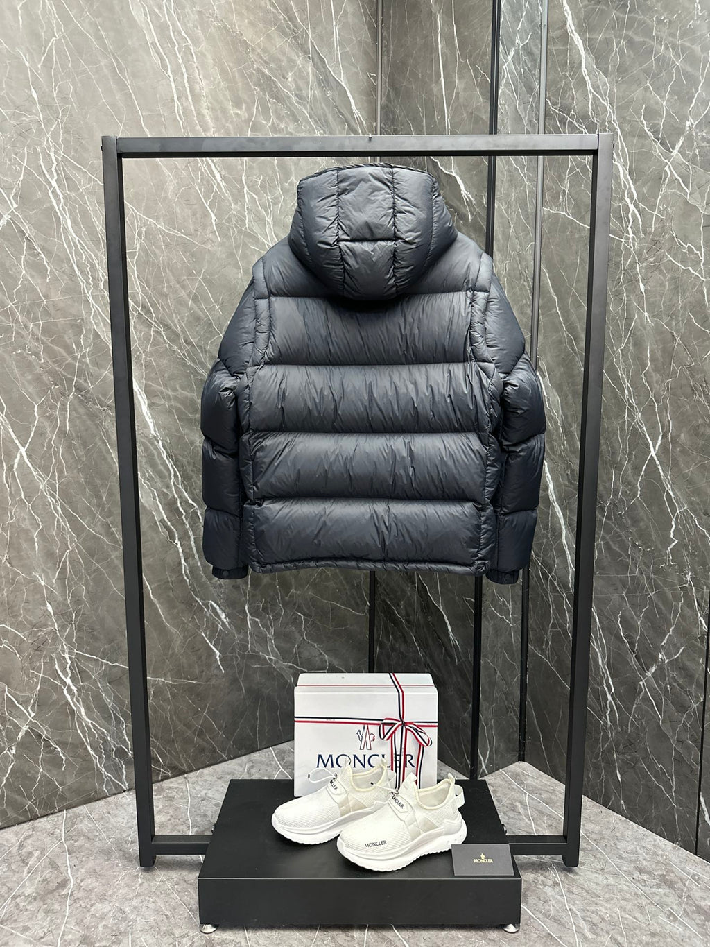 Long back view of hooded puffer jacket, dark quilted fabric and ribbed cuffs