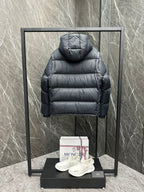 Long back view of hooded puffer jacket, dark quilted fabric and ribbed cuffs