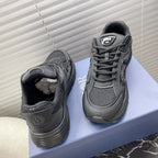 Dior unisex sneakers on box, dark gray lace-up with black padded tongue.