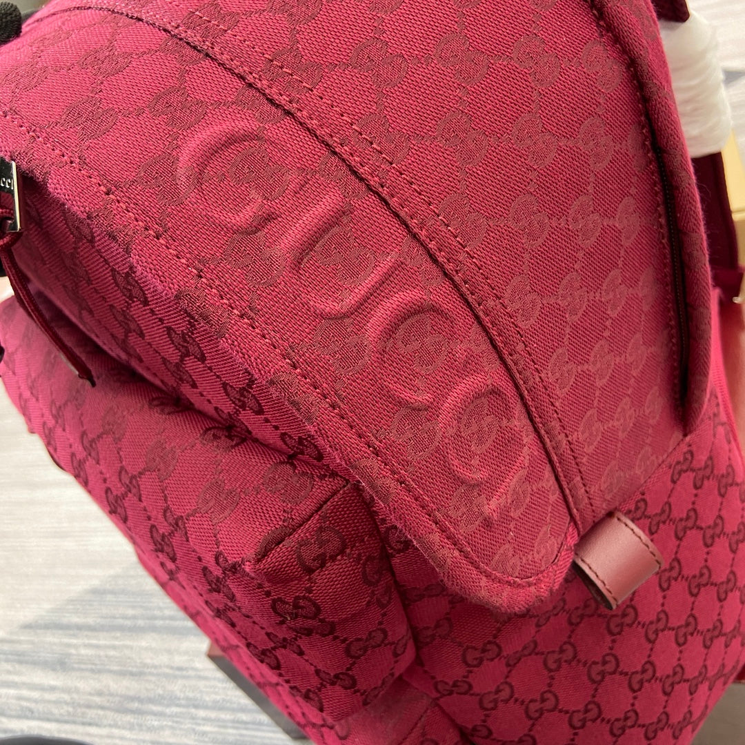 Maroon Gucci backpack side panel with GG jacquard texture and stitched seams.