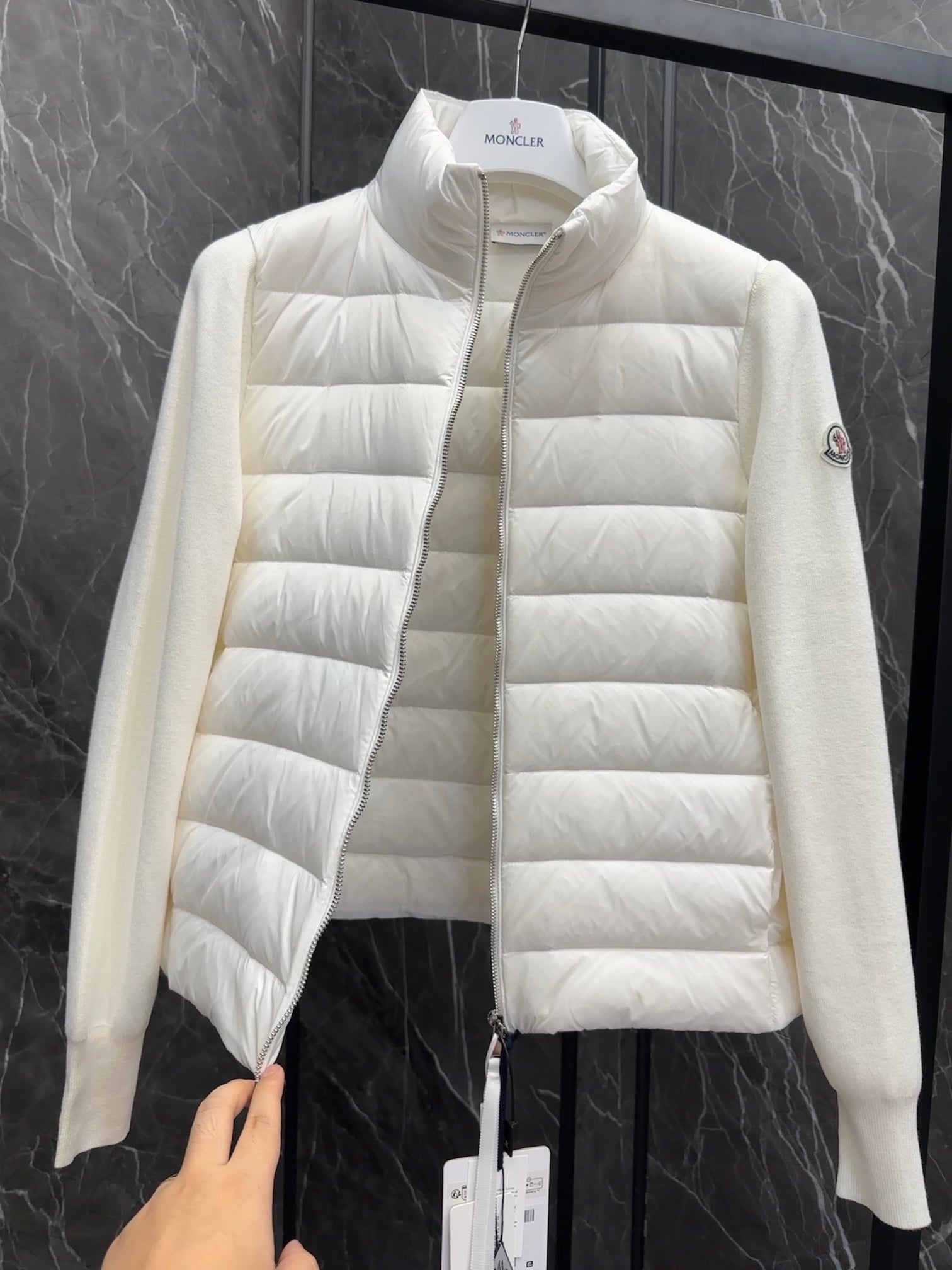 Moncler long padded jacket close-up, light white zipper front with tag held up