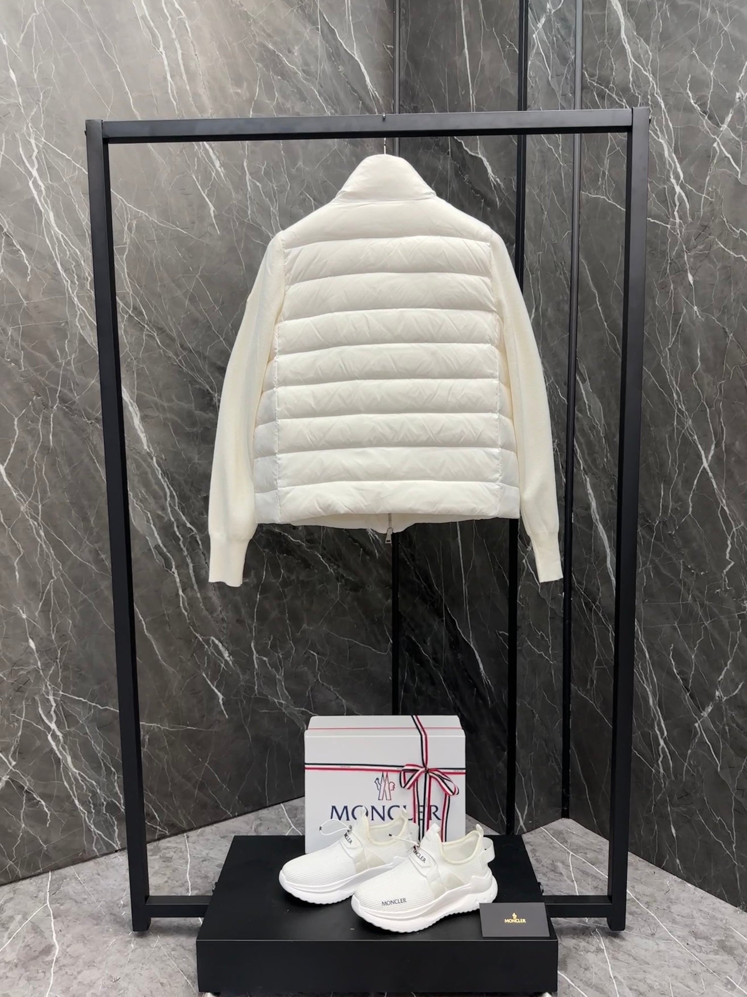 Moncler long padded jacket back view, light white quilted design on display stand