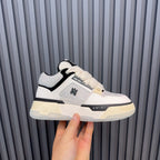 White and black low-top sneakers with cream sole and AMIRI side logo.