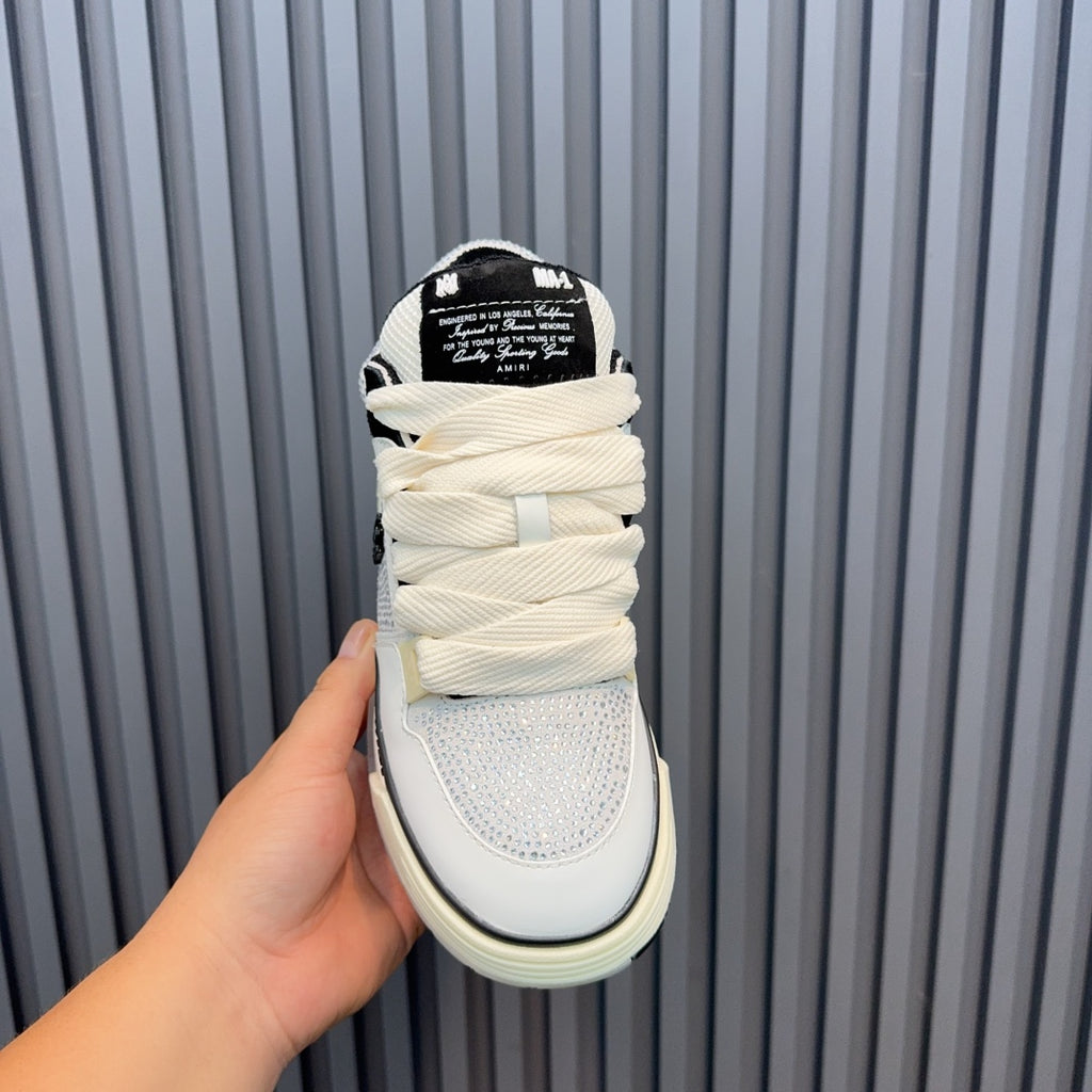 White sneakers with black heel label, cream sole, padded tongue and laces.