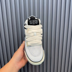 White sneakers with black heel label, cream sole, padded tongue and laces.
