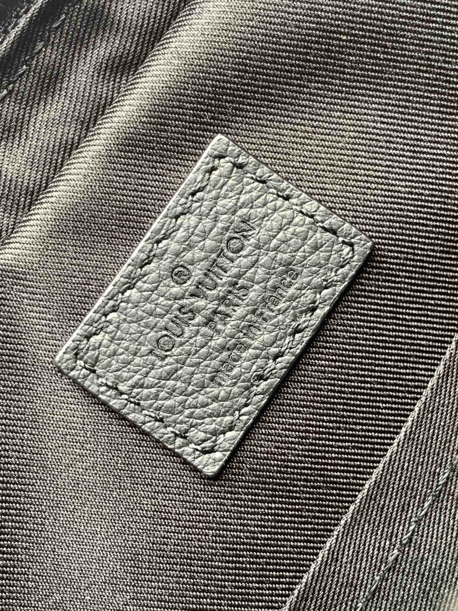 Louis Vuitton bag interior label on textured gray fabric with embossed logo