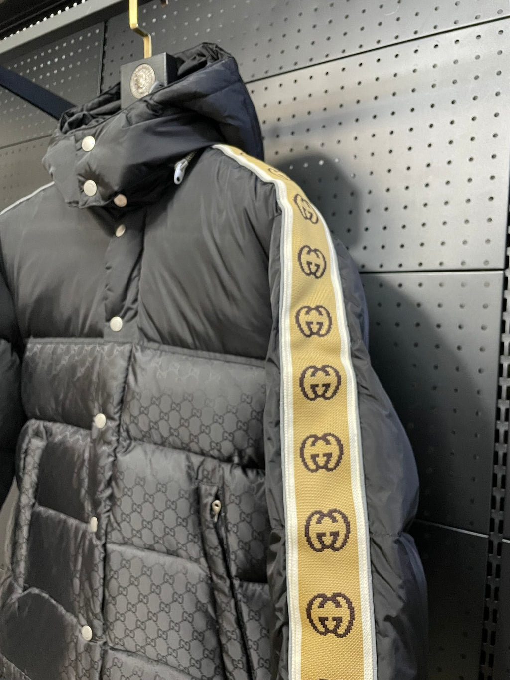 Black hooded puffer jacket with patterned shell and yellow striped sleeve tape