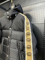Black hooded puffer jacket with patterned shell and yellow striped sleeve tape