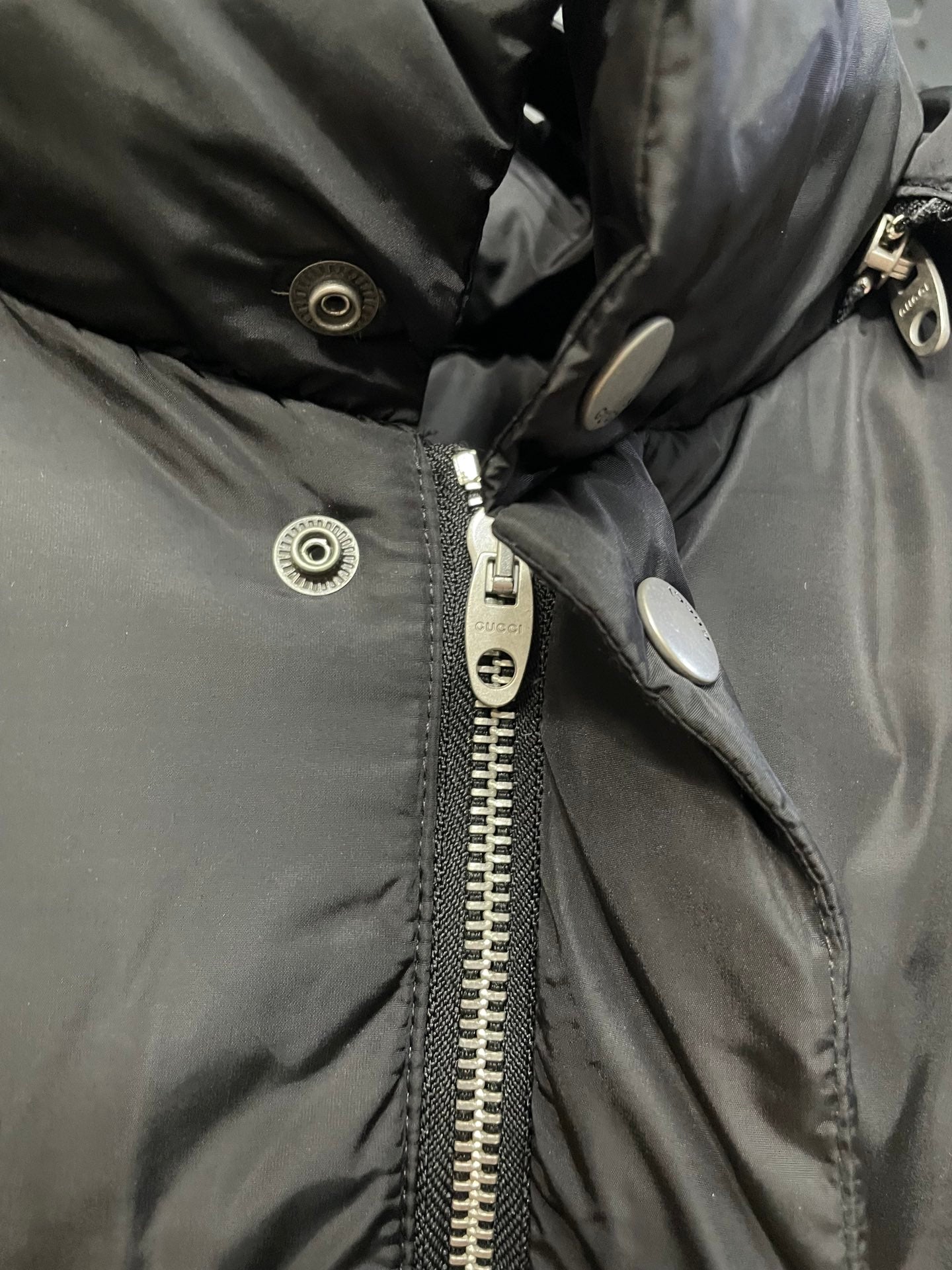 Black puffer jacket close-up with snap placket and metal zipper pull