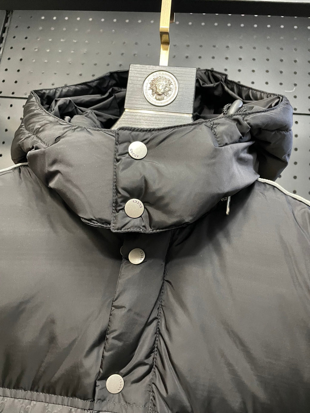 Black hooded puffer jacket with snap buttons and large round logo patch