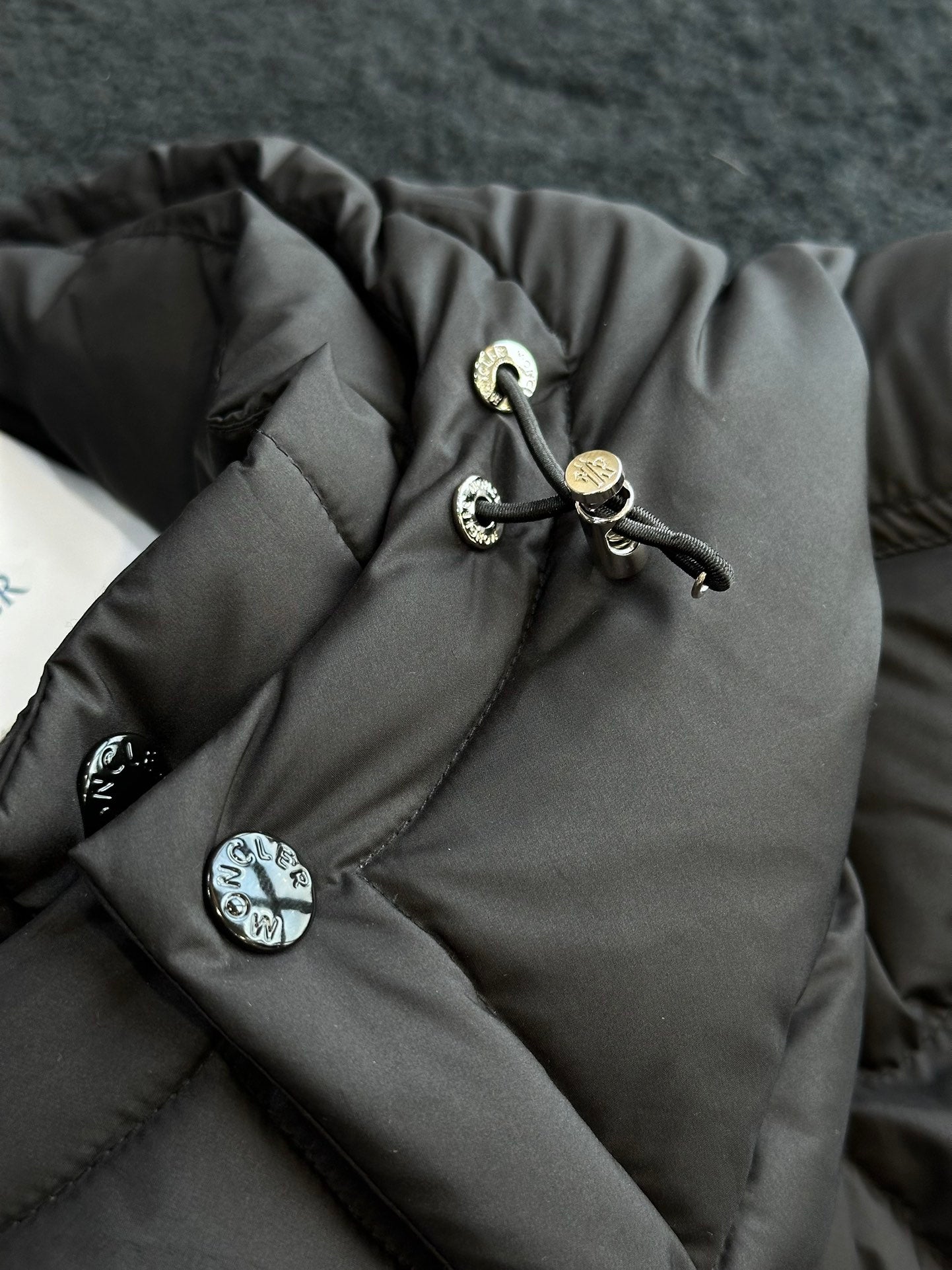 Black puffer jacket sleeve cuff with drawstring and metal cord toggles