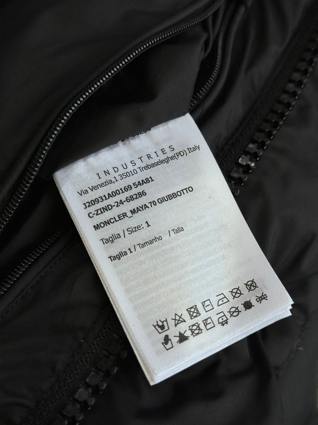 Black puffer jacket care label tag with size and fabric icons