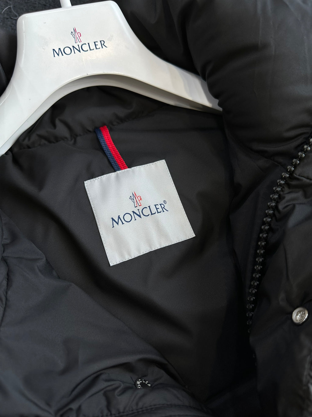 Black puffer jacket neck lining with white tag and red logo trim