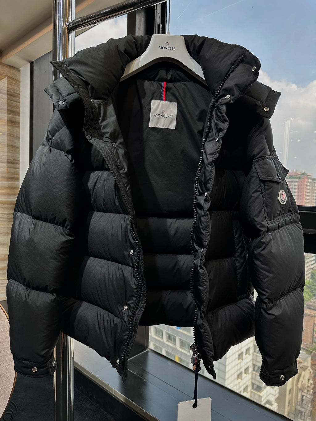 Long puffer jacket in dark black with open front and sleeve logo patch
