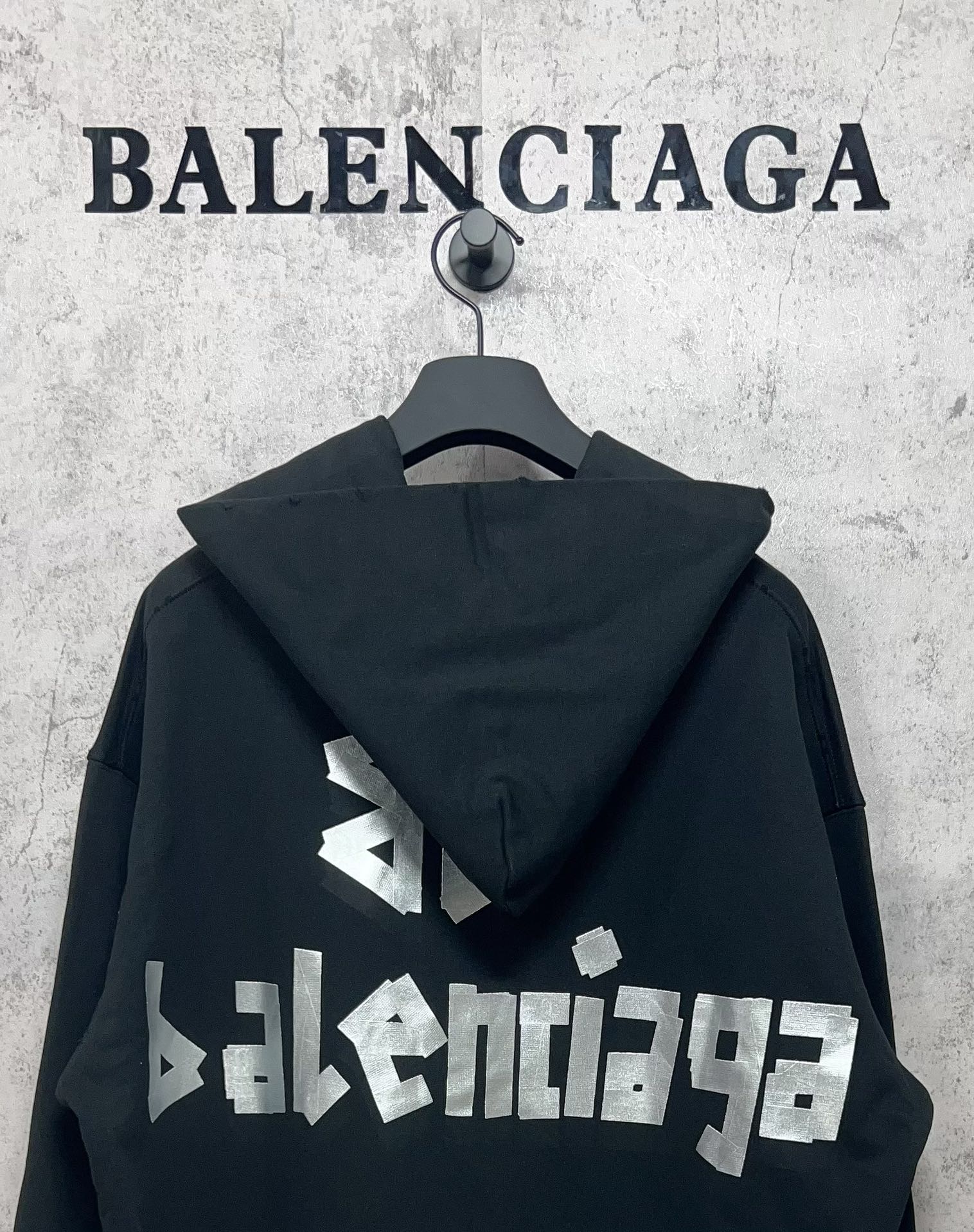 Black hoodie with hood and white Balenciaga logo print on the back