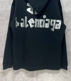 Black hoodie with large white Balenciaga logo print on the back and hem