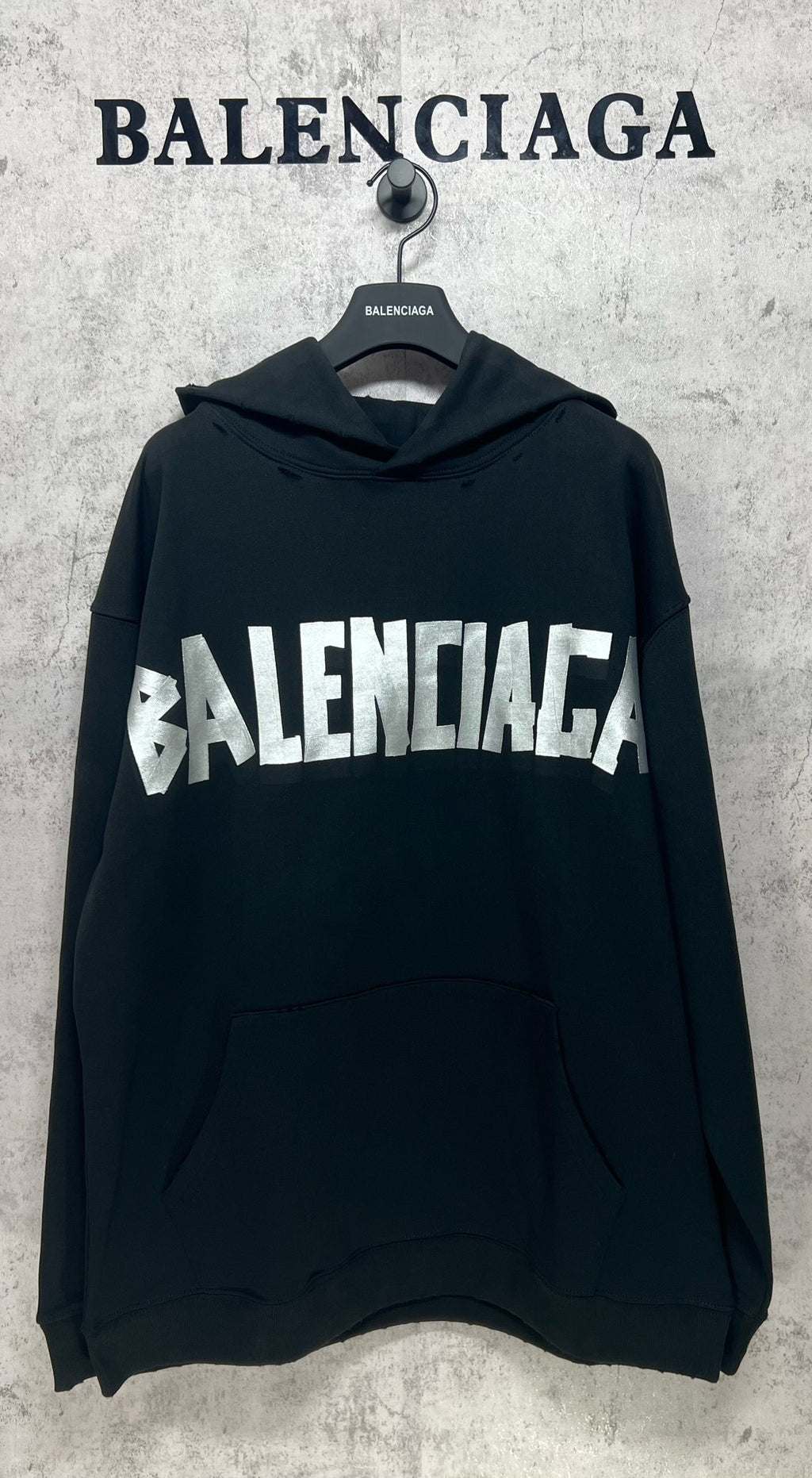 Black long-sleeve hoodie with white Balenciaga logo print and front kangaroo pocket