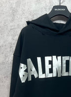 Black hoodie with hood detail and large white Balenciaga logo print on the front