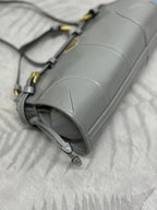 Light gray Prada bag close-up with stitched seams and gold-toned strap hardware.