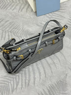 Light gray Prada bag, side view with adjustable strap, zipper compartments, gold hardware.