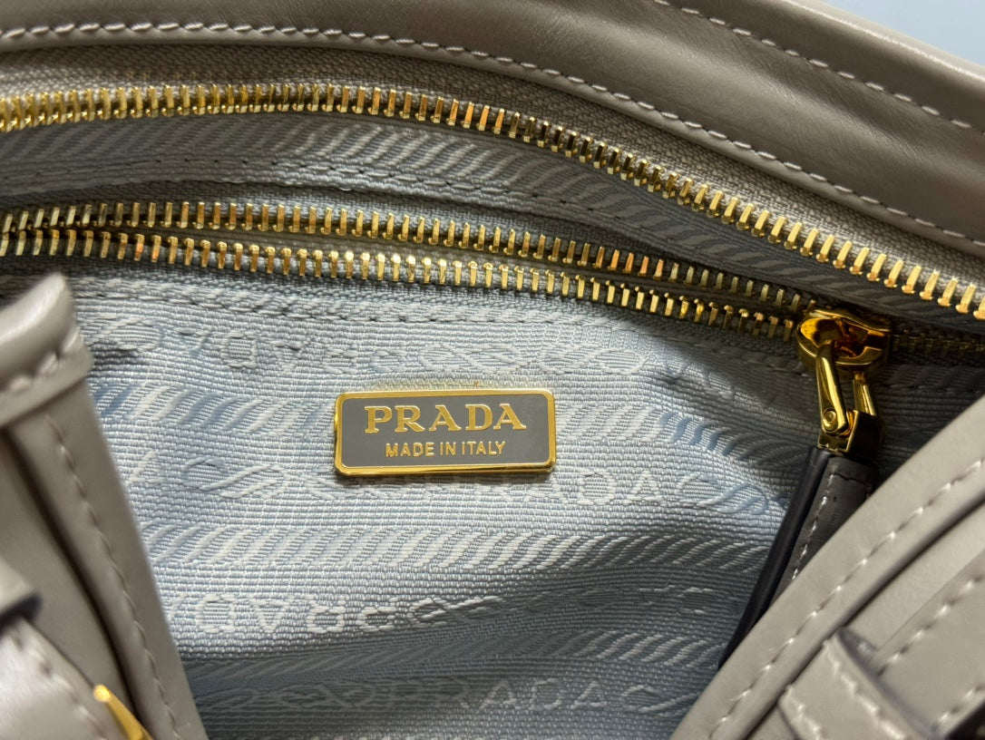 Prada bag interior close-up with gold zipper and 'Prada Made in Italy' leather patch.