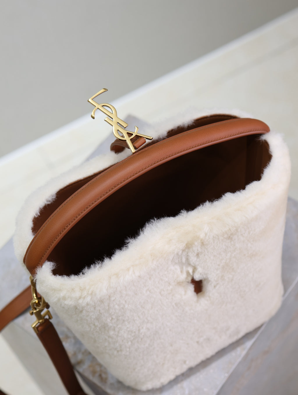 Cream shearling-look YSL bag with gold YSL logo on brown strap, open interior
