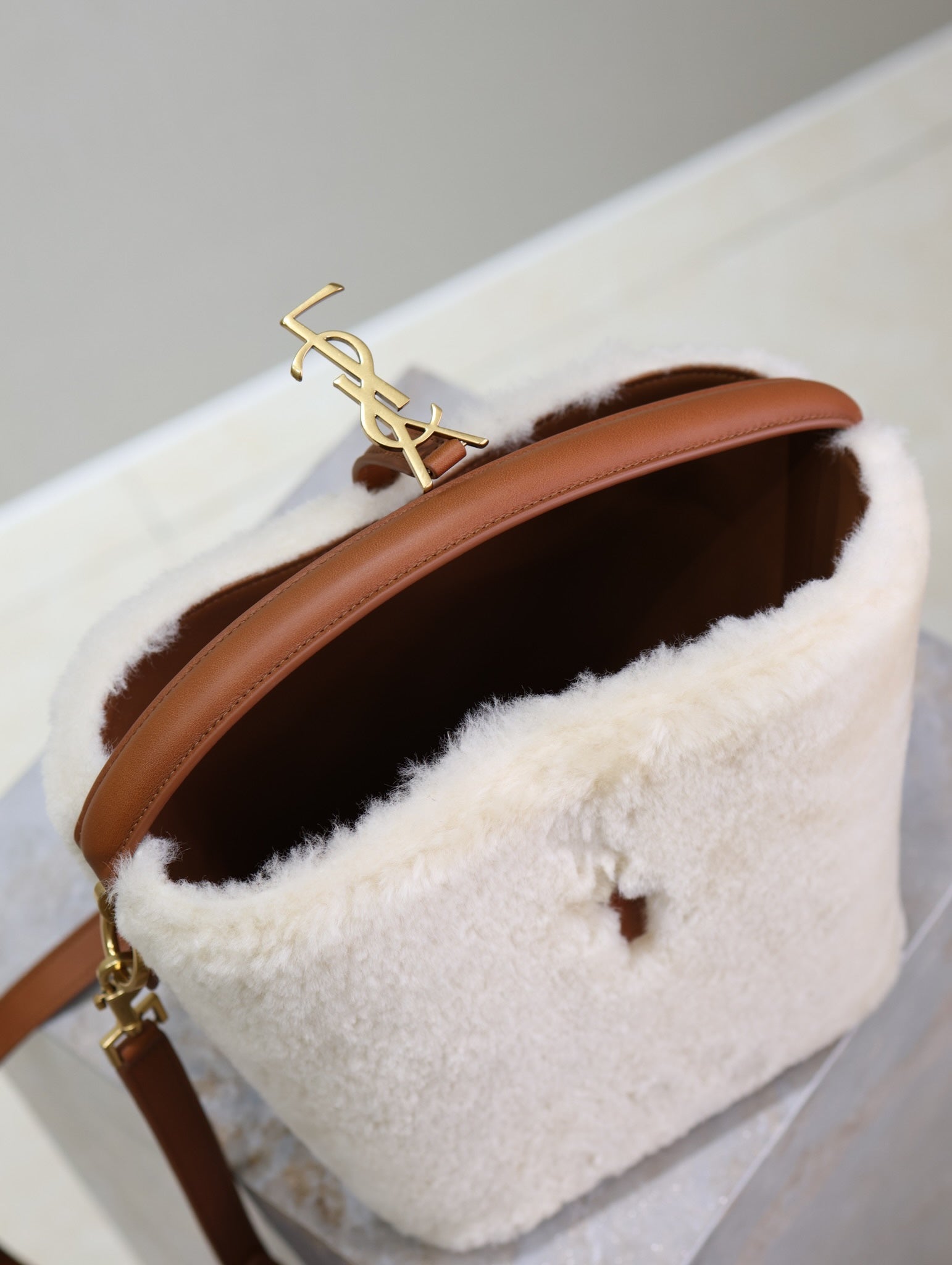 Cream shearling-look YSL bag with gold YSL logo on brown strap, open interior