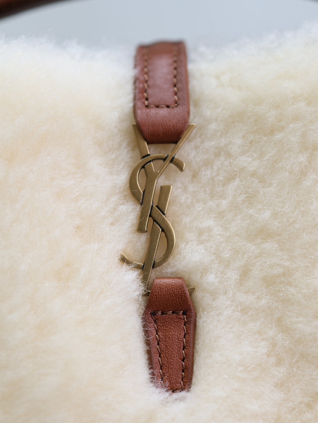 YSL faux fur bag detail: brown leather connector with gold-tone logo hardware