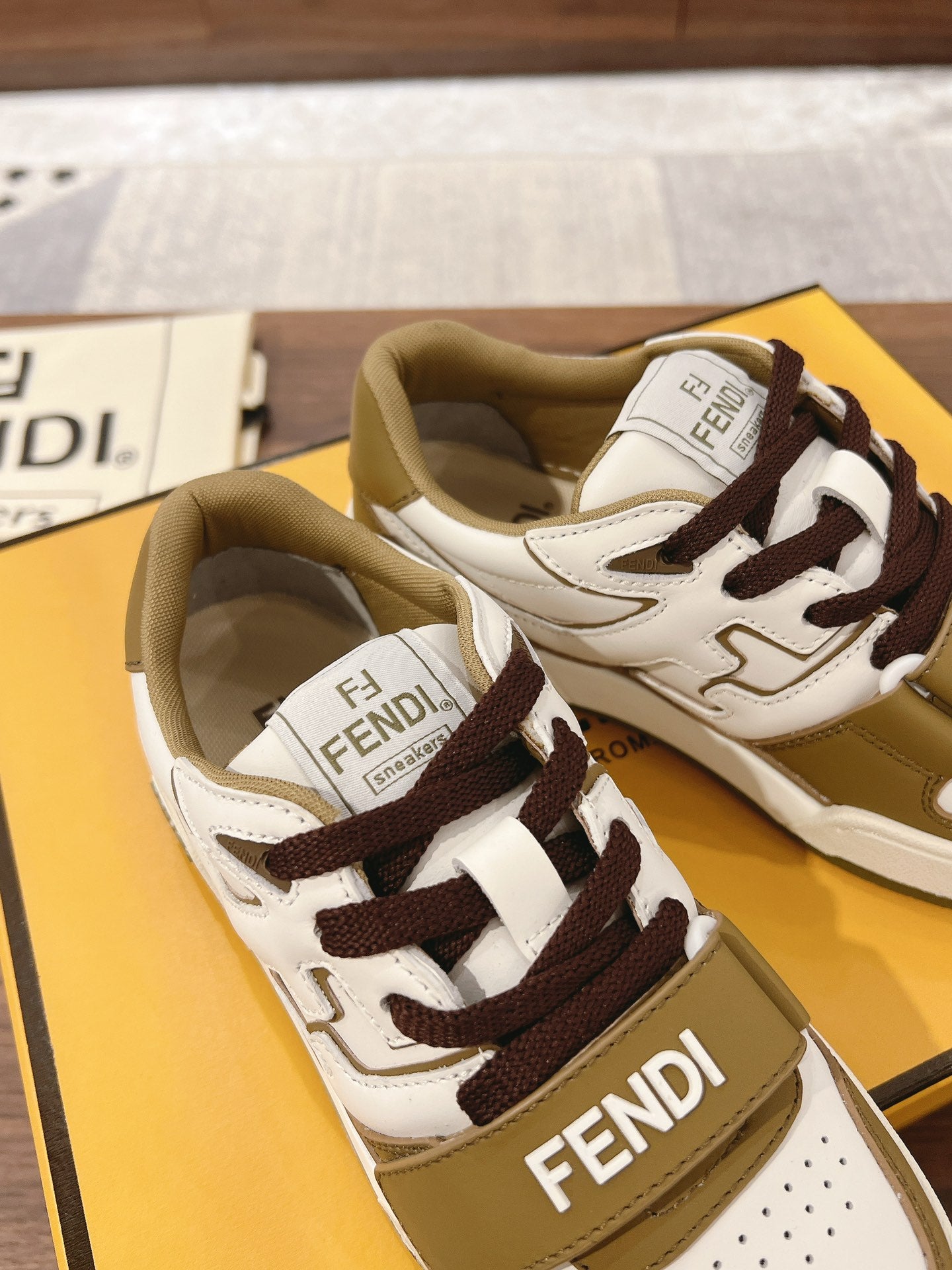 Fendi low-top sneakers with white uppers, tan sides, and dark brown laces in pair view